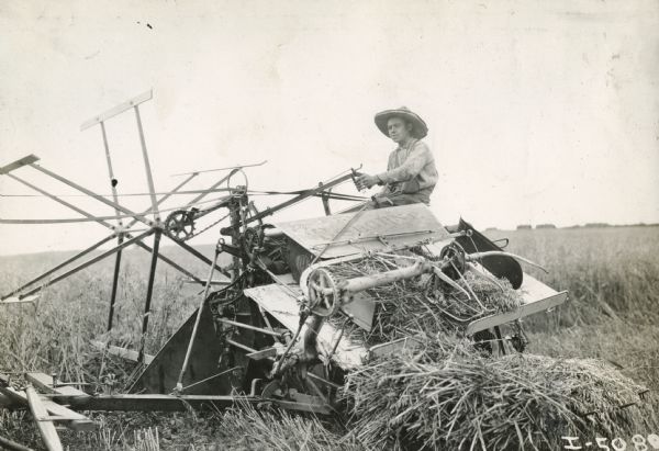 A farmer works in a field with an Osborne grain binder.