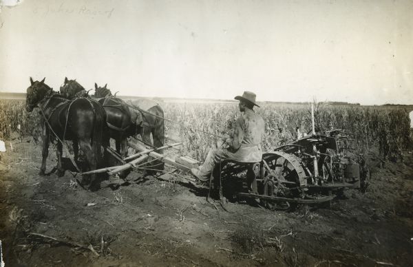 A man operating a horse-drawn McCormick corn binder on Swift Ranch.