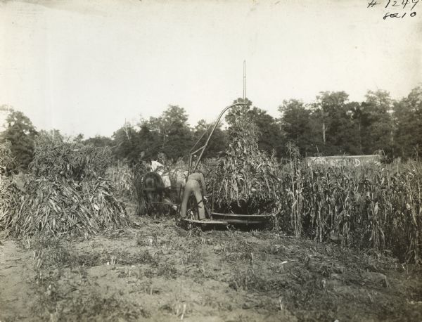 Farmer operating a corn shocker in a field.