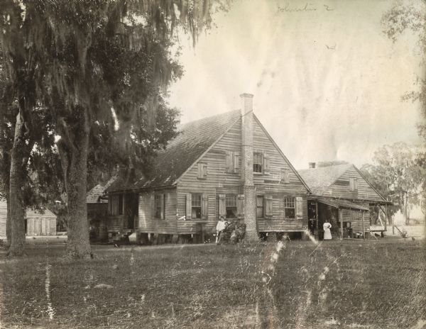 Several individuals pose in front of the residence of C.A. Lowry. The original caption reads: "Mr. Lowry bought 9,000 acres fronting on the Mermentau River and Lake Arthur in 1891.  Before coming to Louisiana, he was in the wholesale drug business at Terre Haute, Indiana.  His plantation has two large irrigating canals upon it which reach out several miles and supply water for adjoining planters.  The house here shown was built a century ago by French settlers."