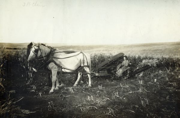 Jake Rascof using a horse-drawn corn binder in a field.