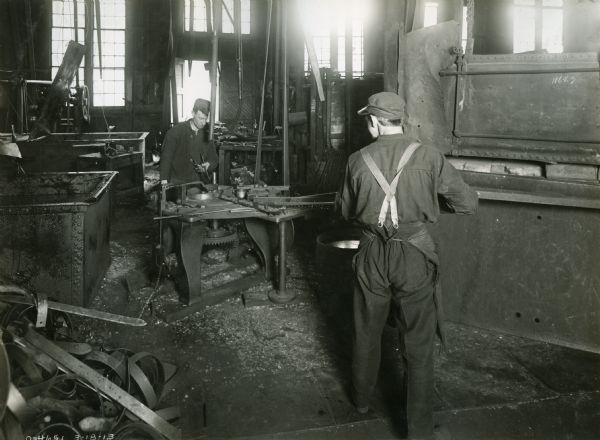Two men manufacturing spring teeth for harrows at International Harvester's Osborne Works. The factory was later known as "Auburn Works."