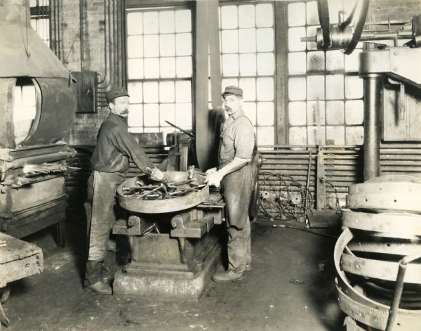 Factory workers work on a steel wheel at International Harvester's Plano Works. Factory was later known as "West Pullman Works."