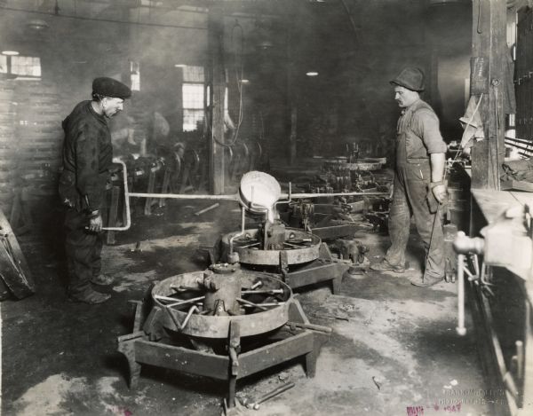 Factory workers pouring hot metal? into a mold or wheel hub at International Harvester's Plano Works. The factory was later known as "West Pullman Works."
