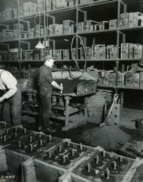 Men working with molds at International Harvester's Plano Works. One worker is standing at a workbench. The factory was later known as "West Pullman Works."
