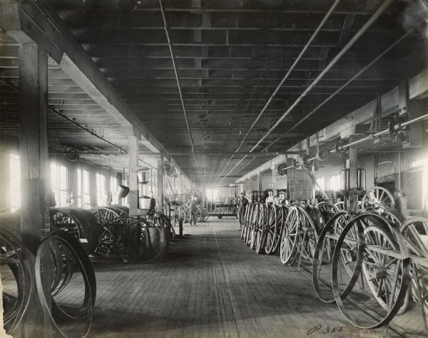 Factory workers are standing in the "wheel room" at International Harvester's Plano Works. The factory was later known as "West Pullman Works."