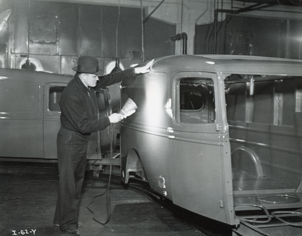 A factory worker shines a lamp on a freshly painted truck body at International Harvester's Springfield Works.