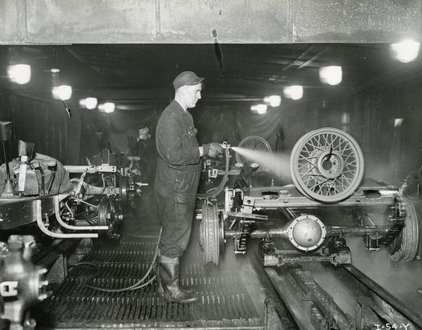 Factory worker spraying a truck rim on the assembly line at International Harvester's Springfield Works.