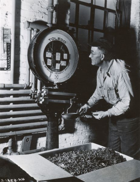 Factory worker weighing parts on a scale at International Harvester's Rock Falls Works.