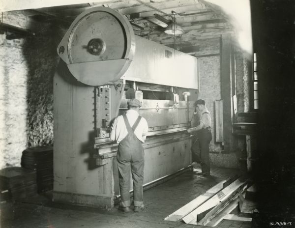 Factory workers using a large press at International Harvester's Rock Falls Works.