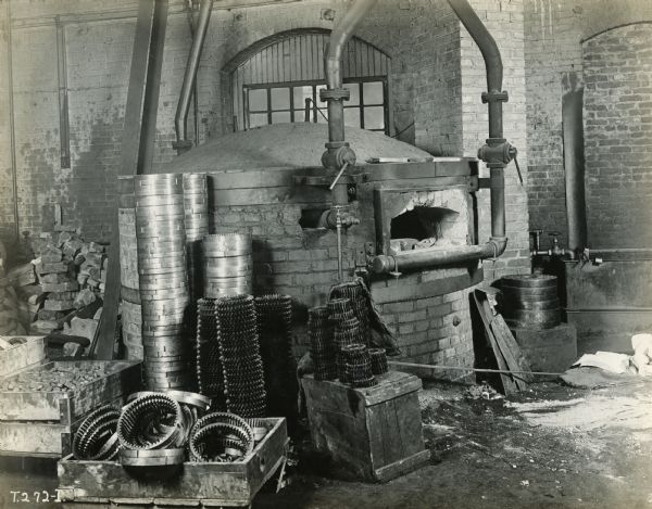 Revolving furnace surrounded by piles of metal truck gears at International Harvester's Akron Works (factory).
