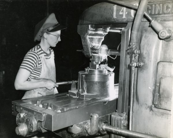 Female factory worker milling the four jaw-faces of a corn picker clutch at International Harvester's Chatham Works. The original caption reads: "This operation requires accurate spacing of the faces to ensure smooth and positive action in the field."