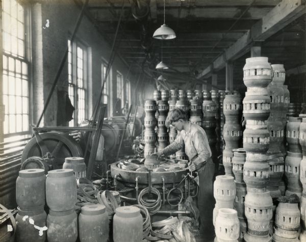 Factory worker manufacturing wagon wheel hubs at International Harvester's Weber Wagon Works.