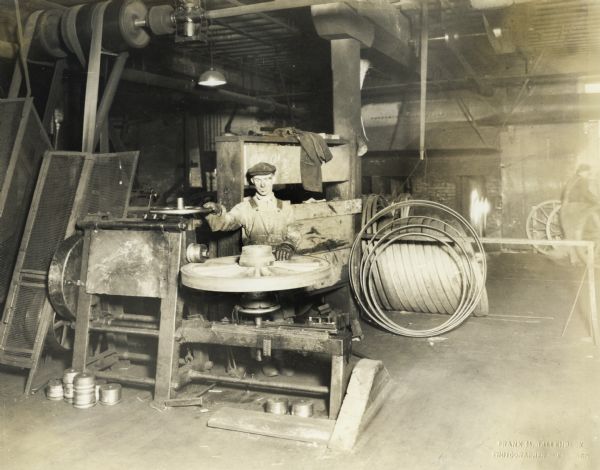 A factory worker with a wagon wheel at International Harvester's Weber Wagon Works.