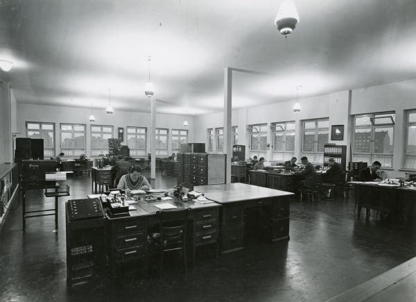 Men and women working at desks in the Hamburg, Germany, office of the International Harvester Company.