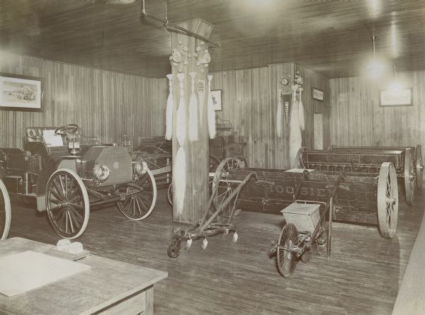 Auto wagon and Hoosier and Empire Jr. seeders on display in the showroom of an International Harvester dealership. Several International Harvester advertising pennants hang on the walls.