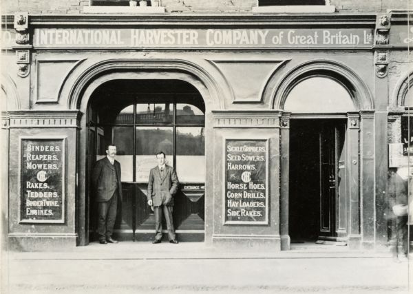 Two men stand in the doorway of an International Harvester general agency (dealership) building of Great Britain.