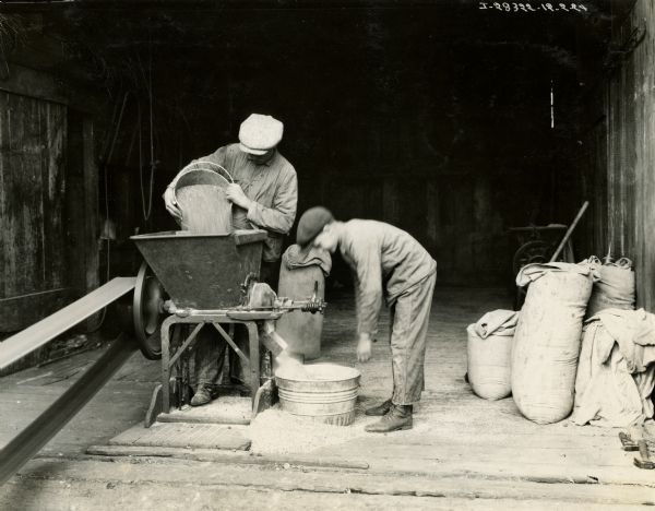 Man and boy using an International feed grinder on the farm of George Bloom.