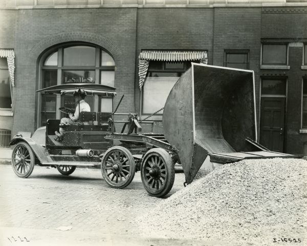 Man operating an International dump truck near the Standard Glass Company on La Salle Street, possibly in Chicago.
