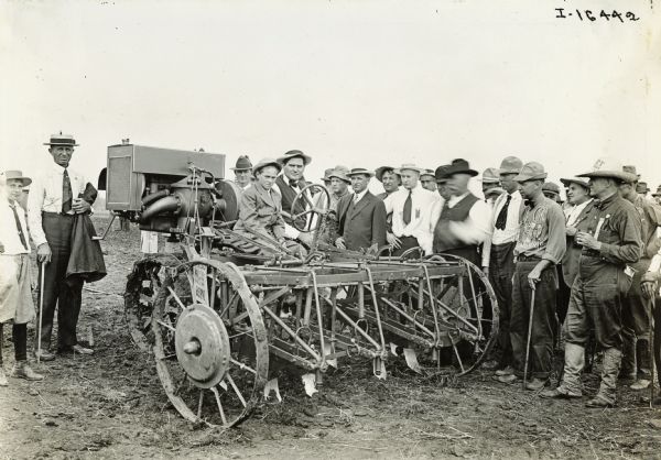 A large group gathers for a group portrait near an experimental motor cultivator(?).