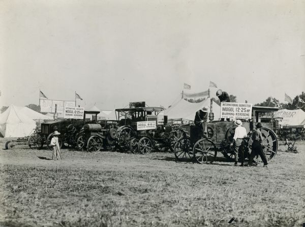 A line up of International Harvester Mogul 12-25 and Mogul 8-16 tractors, and a John Deere tractor in front of tents at the Fremont(?) Tractor Show.
