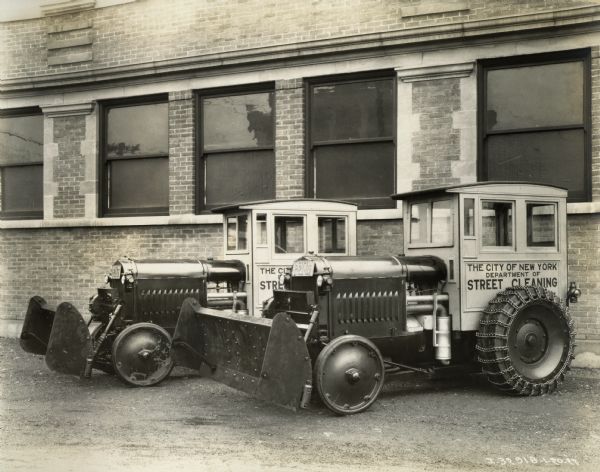 Two International Harvester 10-20 industrial tractors modified to perform street cleaning in New York City. The tractors have enclosed cabs with the text: "The City of New York Department of Street Cleaning".