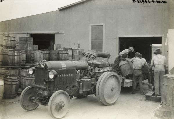 Men unloading barrels from a trailer pulled by a McCormick-Deering 10-20 industrial tractor. The tractor was owned by the San Diego Consolidated Gas and Electric Company.