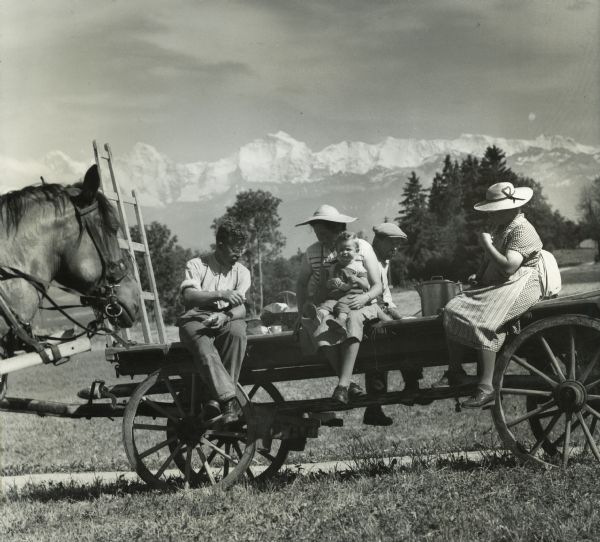 Men, women, and children of the Tschirren family having lunch on a wagon in their field. The Tschirrens had a farm in Niedermuhlern, Switzerland.