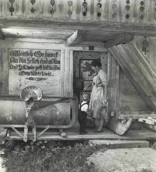 Marie Tschirren and her young son taking a side of lard from a storage building on their farm in Niedermuhlern, Switzerland. A sign above a farm implement seat translates as "mankind, think about your end every hour and every step."