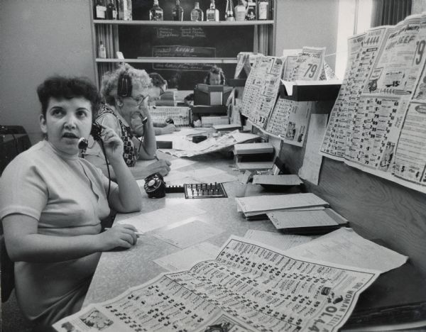 Betty Bakalaya, operator for Hazan's Telephone Supermarket, takes an order over the phone. Her coworkers are in the background.