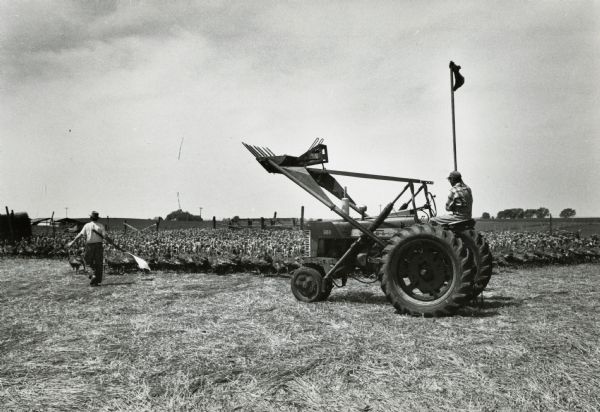 Farmer Hubert Hill using a Farmall 300 tractor with a front-end loader to control a flock of turkeys. The original caption reads: "Hubert Hill's elevated front-end loader and sack on pole help control flock."