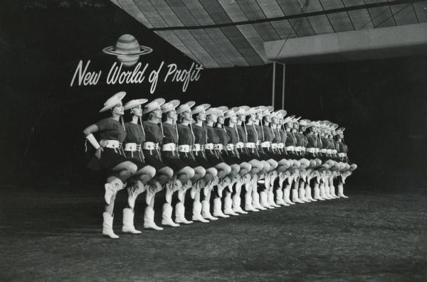 Kilgore Texas Rangerettes forming a chorus line under the sign "New World of Profit" at International Harvester's product introduction show.