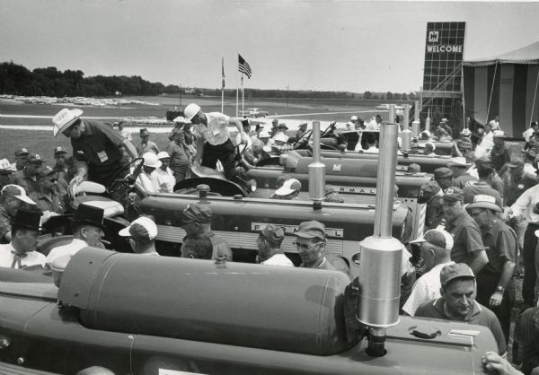 Visiting dealers look over International Harvester's 1958 line of tractors at a product introduction show. The photograph was taken near the show's dining tent.