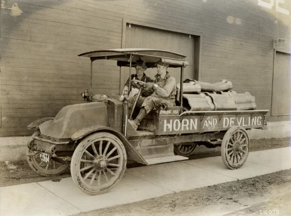 Two men drive an International Model F (or 31) truck filled with large metal pieces for the Horn and Devling Company.c
