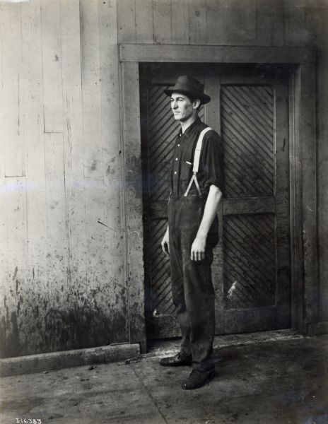 A International Harvester employee stands near a factory door. The factory was most likely located in Chicago.