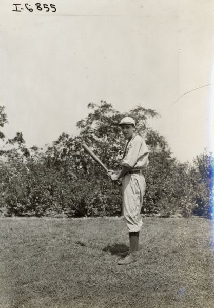 Man in a baseball uniform posing with a bat. The man may have been a member of an International Harvester company baseball team.