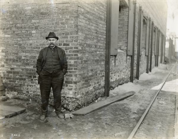 Man, possibly an employee of International Harvester's Deering Works, standing outside a factory building.