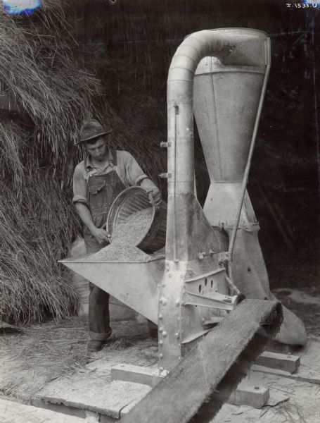 A man using an International Harvester No. 1 Hammer Mill on the farm of Herman Wilke.
