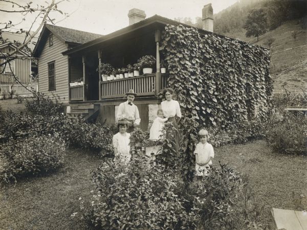 A family of five posing in front of an International Harvester "company house" in the coal mining town of Benham.