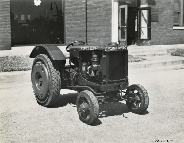 McCormick-Deering I-12 tractor on a street in front of a building.