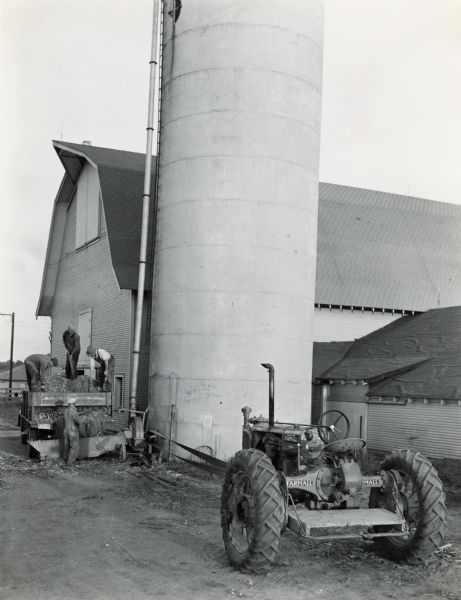 Men loading corn ensilage into a silo blower powered by a Farmall F-30 tractor on the Purdue University Livestock Farm.