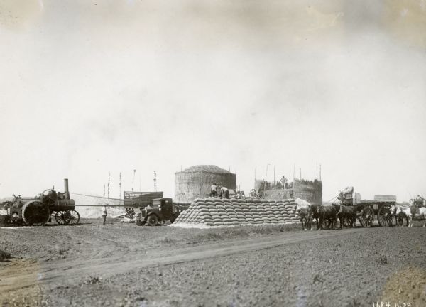A tractor and a model S-24 truck are in the distance as men process corn and pile sacks for shipment. The men worked for Balbi Brothers(?) of the "Estacion Roja F.C.C.A." in Argentina(?). According to the original caption, the corn was hauled 2 leagues to the station to be shipped out. 15,000 bags were to be transported at the rate of 600 per day; 100 bags on every trip, 50 on the truck and 50 on the trailer.