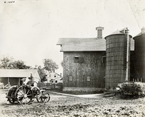 An Mogul 10-20 H.P. tractor powering a silo filler. A man is standing on a wagon behind the tractor.