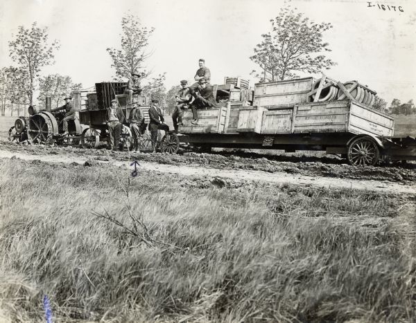 An International Harvester Mogul 10-20 H.P. tractor pulling a trailer for the Aviation Section No. 507 of the U.S. Army Signal Corps. The trailer appears to be filled with crates of rubber tires. The fourth man from the left is possibly Cyrus McCormick III (Cyrusie).