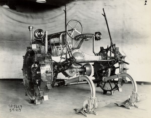 Engineering photograph of a Farmall Regular tractor with electric lights and attached two-row middle-buster.