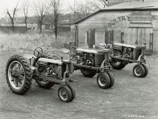 Farmall F-14, F-20 and F-30 tractors lined up in a yard near a poultry building. The photograph was taken by the company's Kankakee branch.