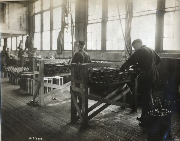 Workers stand at their stations in International Harvester's Milwaukee Works (factory).