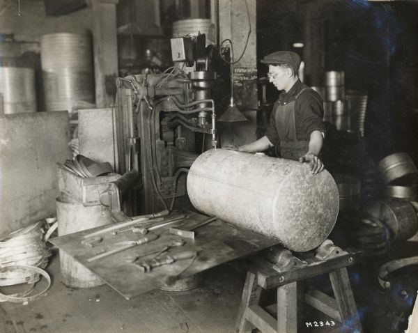 A worker operates a large machine at International Harvester's Milwaukee Works (factory).