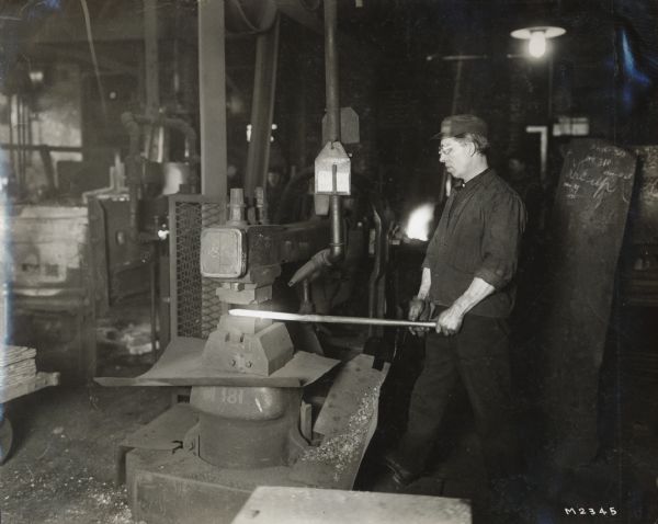 A worker prepares to stamp a heated metal rod at International Harvester's Milwaukee Works (factory).