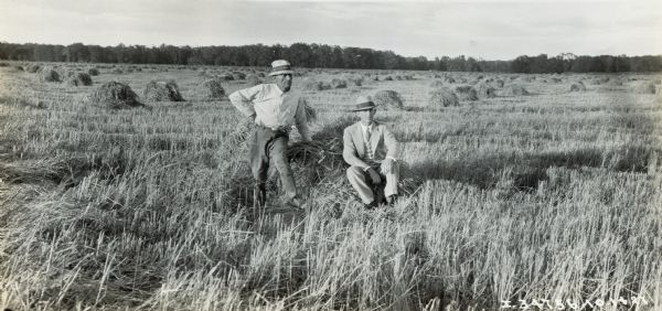 Two men, one identified as P.T. Schraider, pose in the middle of a field.